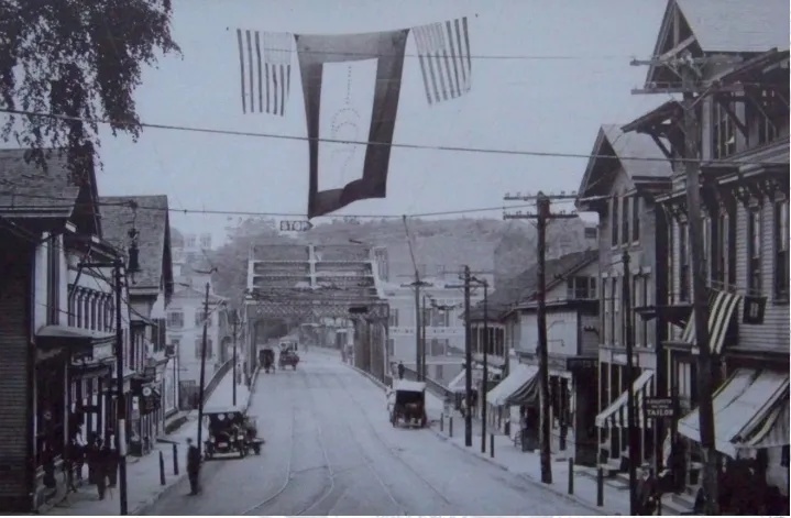 Black and white photo of a small town street with banners overhead
