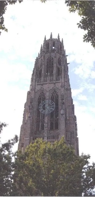 Tall gothic cathedral tower with intricate stonework and a large clock