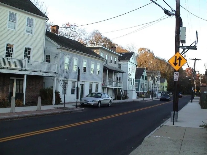 Quiet street with white houses and parked cars on a clear day